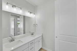 Bathroom with double vanity and baseboards