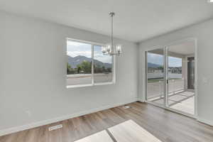 Unfurnished dining area with a mountain view, healthy amount of natural light, a chandelier, and wood finished floors