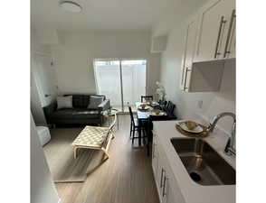 Kitchen featuring white cabinetry, light countertops, dark wood-type flooring, and open floor plan