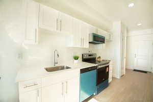 Kitchen featuring stainless steel electric stove, white cabinetry, dishwasher, recessed lighting, and light wood finished floors