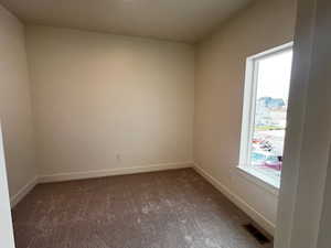 Unfurnished room featuring healthy amount of natural light and carpet