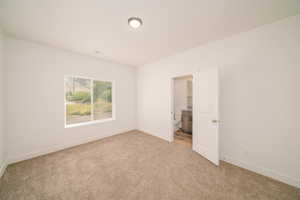 Unfurnished bedroom with light carpet and ensuite bathroom
