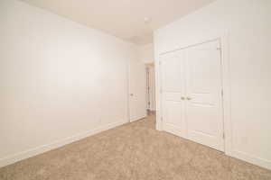 Unfurnished bedroom featuring light carpet and a closet