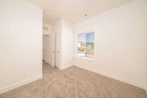 Spare room with light carpet and baseboards