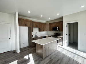 Kitchen with a kitchen island, recessed lighting, stainless steel appliances, dark wood-type flooring, and light stone countertops