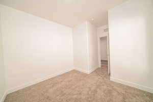 Unfurnished room featuring baseboards and light carpet