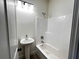 Bathroom with shower / washtub combination and dark wood finished floors