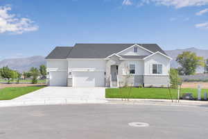 View of front of home with a mountain view, driveway, an attached garage, a shingled roof, and brick siding