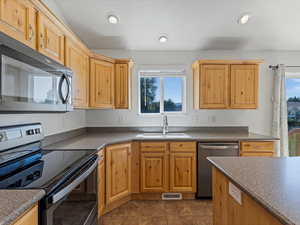 Kitchen featuring stainless steel appliances, dark countertops, dark tile patterned flooring, and recessed lighting