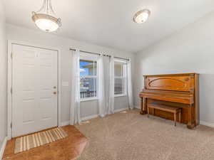 Foyer with light colored carpet, light tile patterned floors, and lofted ceiling