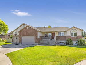 Single story home with a front lawn, brick siding, and a garage