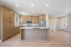 Kitchen featuring plenty of natural light, stainless steel appliances, a kitchen island with sink, recessed lighting, and light stone counters
