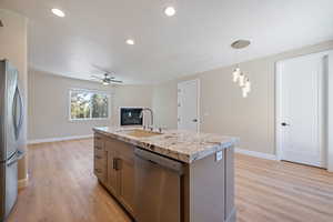 Kitchen with appliances with stainless steel finishes, ceiling fan, light wood finished floors, hanging light fixtures, and recessed lighting