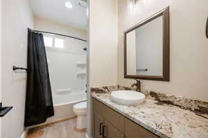 Bathroom featuring vanity, shower / bathtub combination with curtain, and wood finished floors