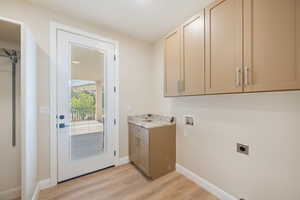 Laundry area featuring electric dryer hookup, cabinet space, washer hookup, and light wood-style floors