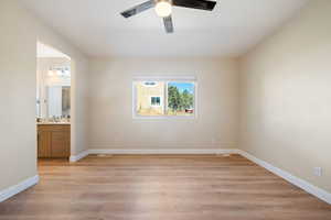 Unfurnished bedroom with light wood-style flooring, ensuite bath, and ceiling fan