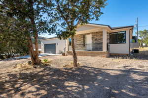 Ranch-style home with covered porch, a garage, stone siding, driveway, and stucco siding
