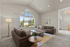 Living area with lofted ceiling, light carpet, recessed lighting, and a chandelier