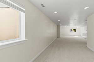 Corridor featuring light colored carpet, recessed lighting, and a textured ceiling