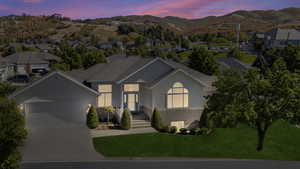 Ranch-style house with stucco siding, an attached garage, concrete driveway, a lawn, and a shingled roof