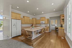 Kitchen featuring plenty of natural light, white appliances, light countertops, crown molding, and light brown cabinets
