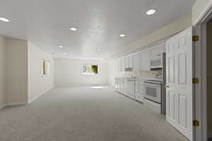 Kitchen with white cabinetry, white appliances, recessed lighting, light countertops, and light colored carpet