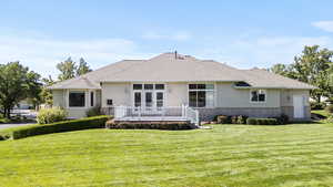 Rear view of property with a yard, brick siding, and a shingled roof