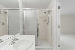 Full bath with a stall shower, a textured ceiling, and vanity