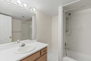Bathroom with bathtub / shower combination, light tile patterned floors, vanity, and a textured ceiling