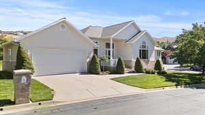 Ranch-style home with stucco siding, driveway, a garage, and a front lawn