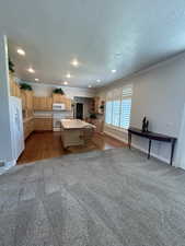 Kitchen with open floor plan, light countertops, recessed lighting, ornamental molding, and white appliances
