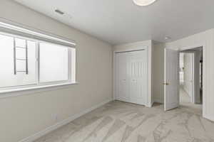 Unfurnished bedroom featuring light carpet, a closet, and a textured ceiling