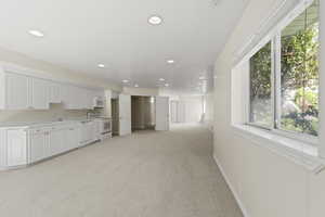 Kitchen with white cabinets, light colored carpet, light countertops, white appliances, and recessed lighting