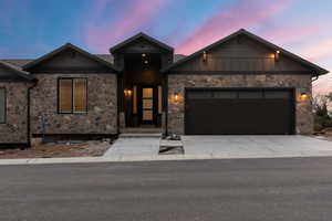 View of front of home with an attached garage, concrete driveway, board and batten siding, and stone siding