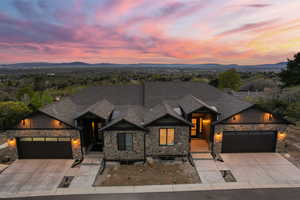 View of front of house with board and batten siding, stone siding, an attached garage, concrete driveway, and a mountain view