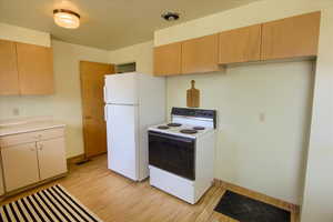Kitchen featuring electric range, light countertops, and light wood-type flooring