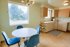 Kitchen with light wood-style floors, light countertops, a chandelier, and hanging light fixtures