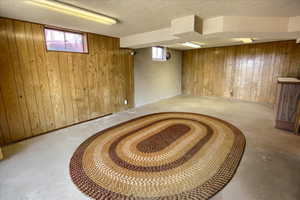 Below grade area with wood walls and a textured ceiling