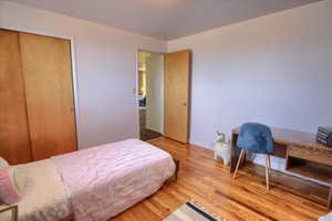 Bedroom featuring wood finished floors, a desk, and a closet