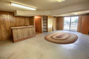 Bar area featuring wooden walls, a textured ceiling, and concrete floors