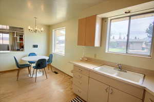 Kitchen with light wood finished floors, light countertops, healthy amount of natural light, and hanging light fixtures