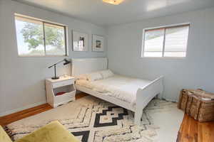 Bedroom with wood finished floors and multiple windows
