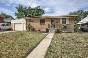 Ranch-style house featuring brick siding, an attached garage, a front yard, and concrete driveway