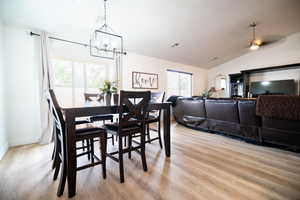 Dining room featuring vaulted ceiling, light wood-style flooring, and a chandelier