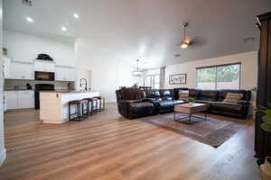 Living room with light wood-type flooring, ceiling fan, recessed lighting, and high vaulted ceiling