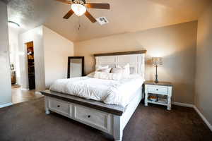 Bedroom with a textured ceiling, carpet, vaulted ceiling, and a ceiling fan