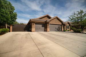 View of front of property featuring a garage, stone siding, driveway, stucco siding, and a gate