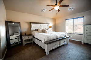 Bedroom featuring a textured ceiling, dark carpet, vaulted ceiling, and ceiling fan