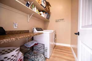 Laundry room featuring light wood finished floors and washer and clothes dryer