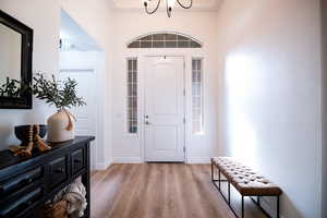 Foyer entrance with light wood-type flooring and a chandelier